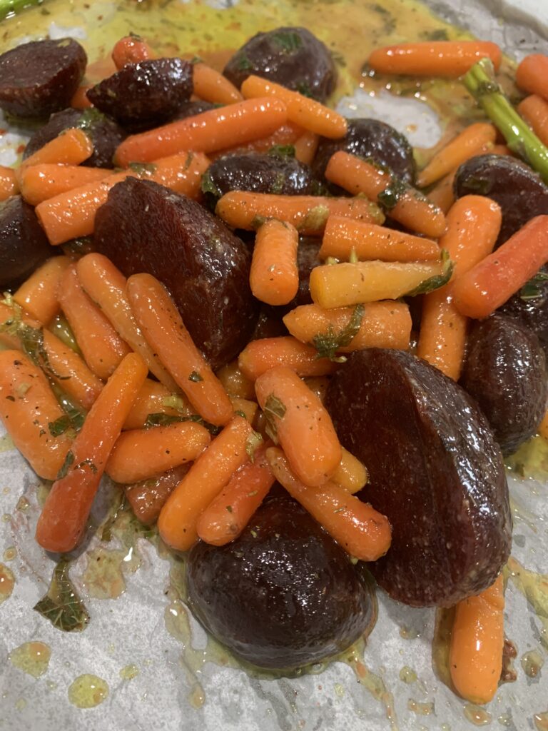 Roasted beets and carrots on a baking tray with parchment paper