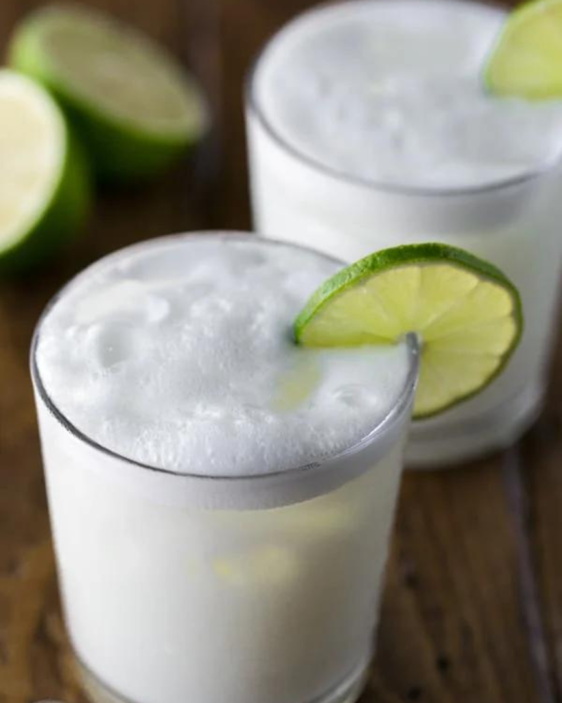 "creamy limeade with ice and lime wedge on wooden table"
