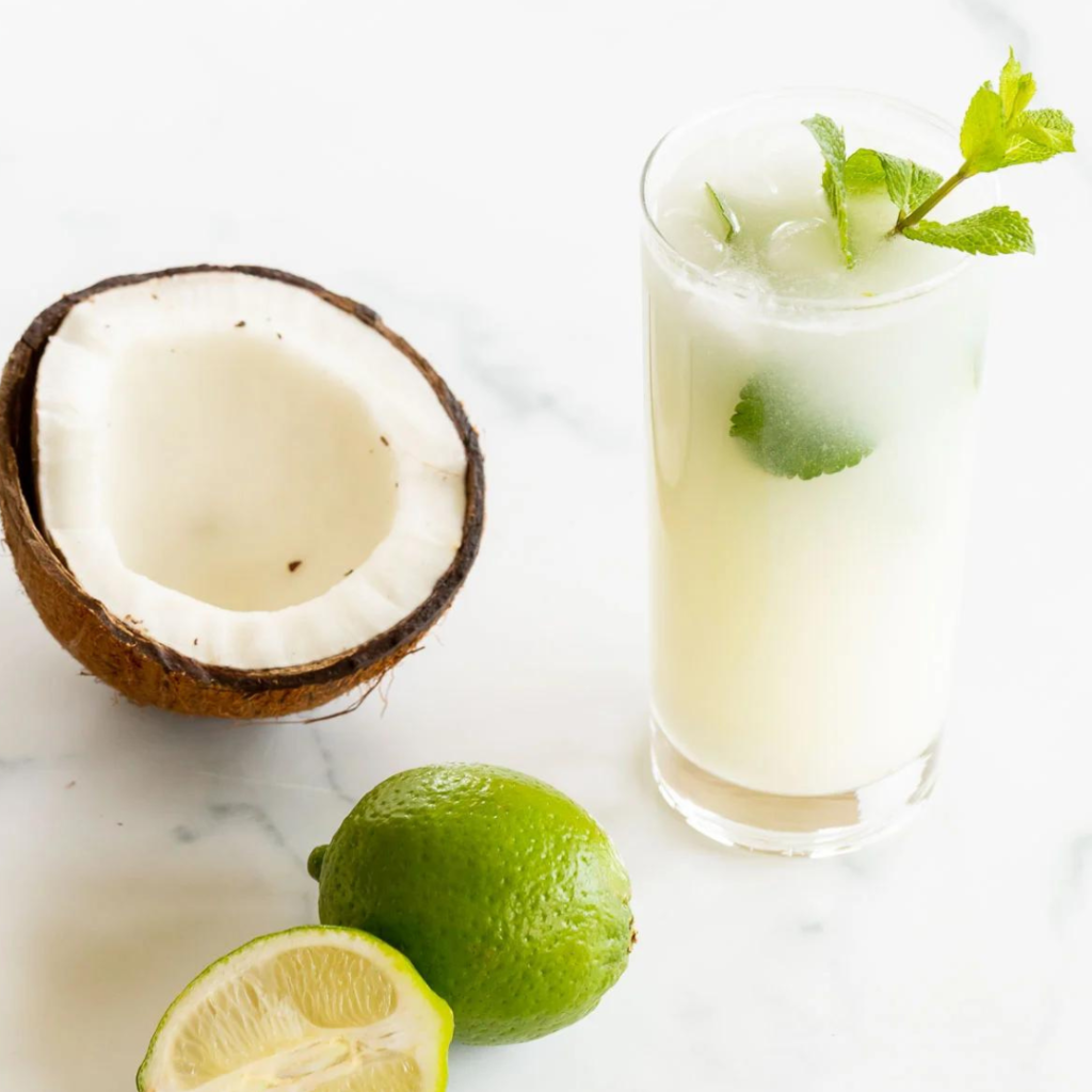 "coconut lemonade with coconut in the shell and lime whole and wedge"