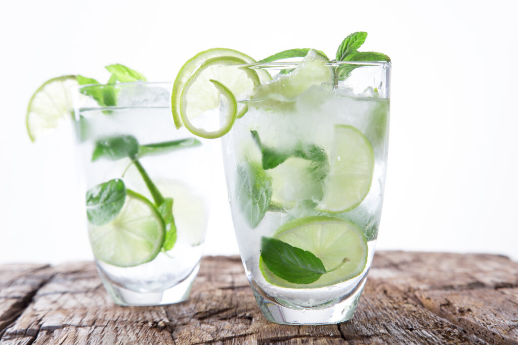 "limeade with ice and limes in clear glass on wooden surface"