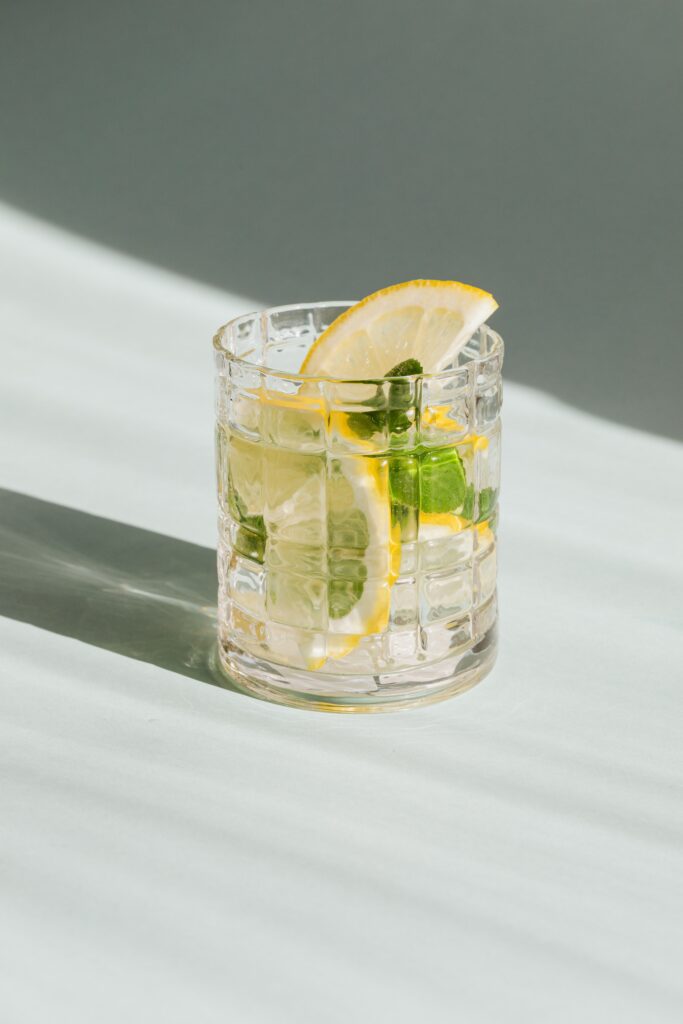 "A drink in clear glass garnish with mint leaves and lemon"