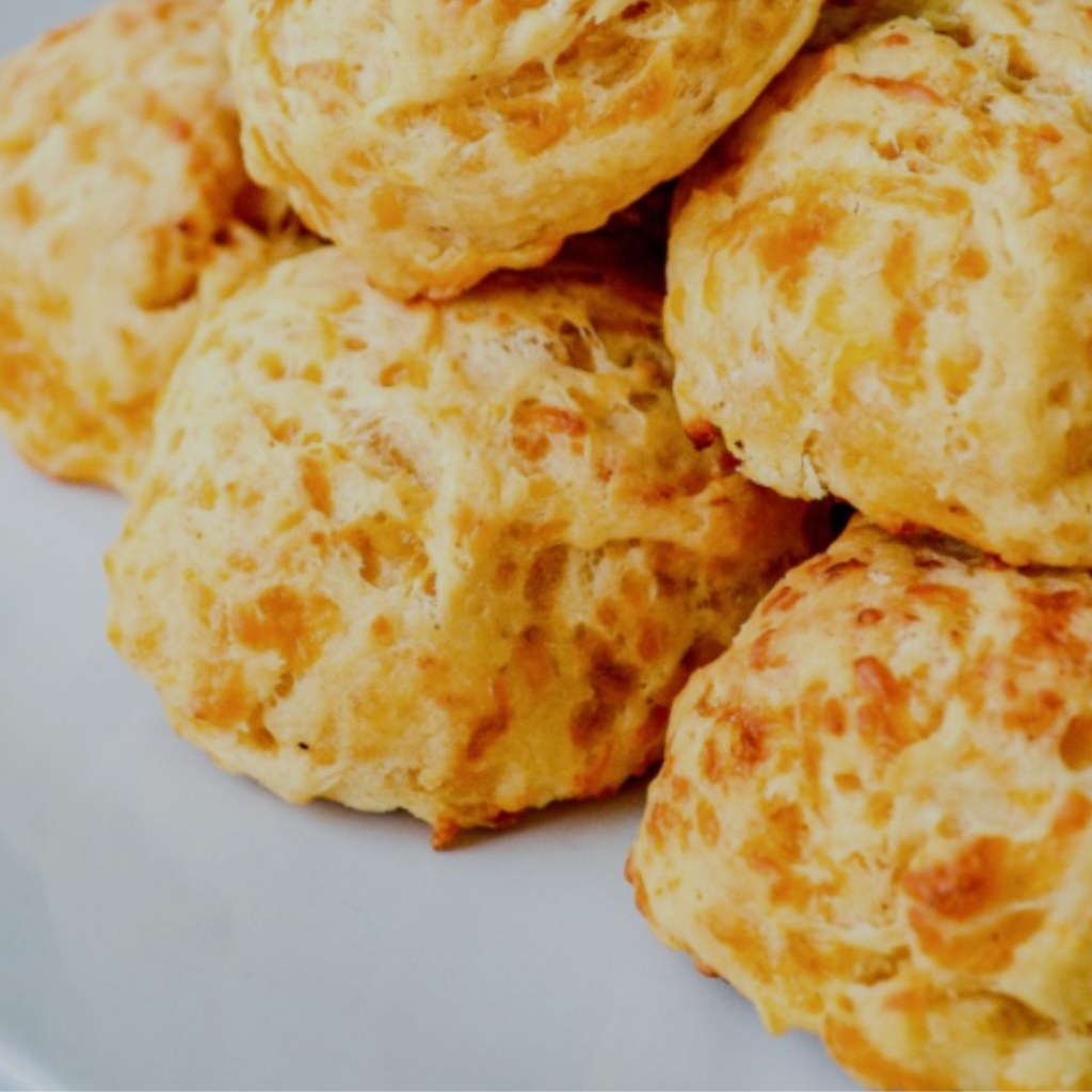 "Cheesy savory biscuits stacked up on a white background"