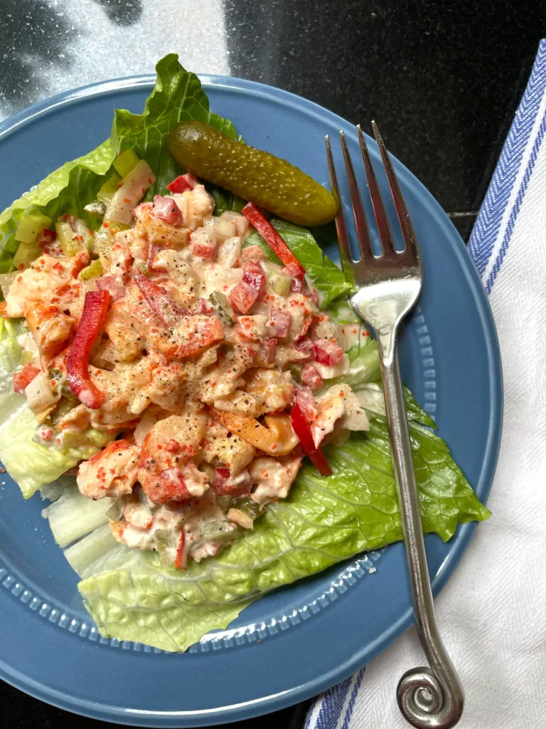 "Lobster salad on lettuce on a blue plate with fork on plate"