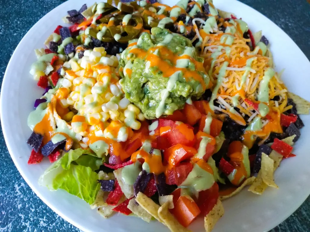 "veggie taco bowl with lettuce, onions, tomatoes, beans, guacamole and sauce