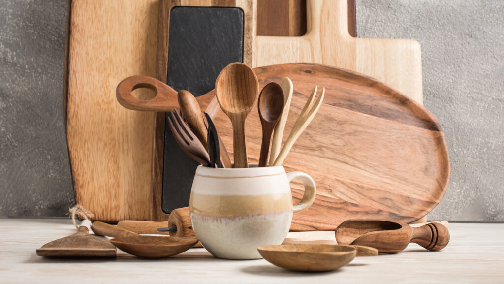 "Kitchen accessories made out of acacia wood and ceramic on a wood background and gray tile back drop