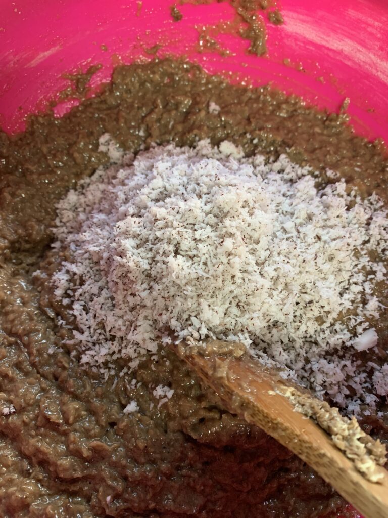 "Adding coconut to a bowl of sweet potato mixture"