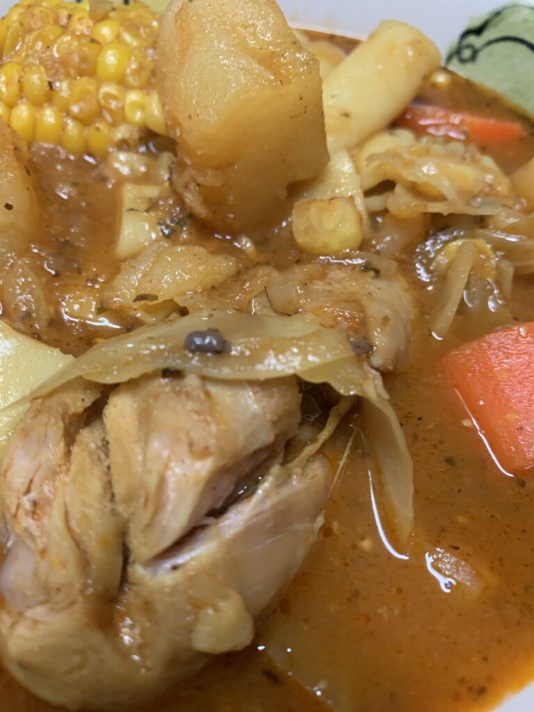 "chicken drumstick, potatoes, corn, carrots in a soup broth"