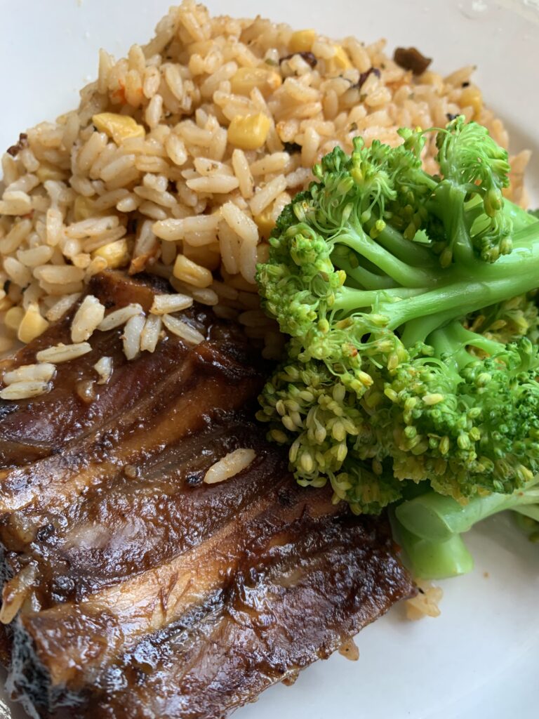 "A plate with peas and rice, cooked broccoli and bbq rib