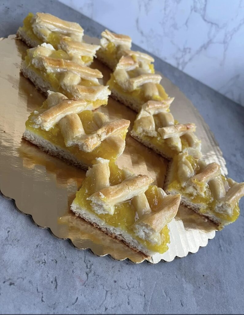 "A pastry on a gold cake holder cut into slices filled with a pineapple filling"