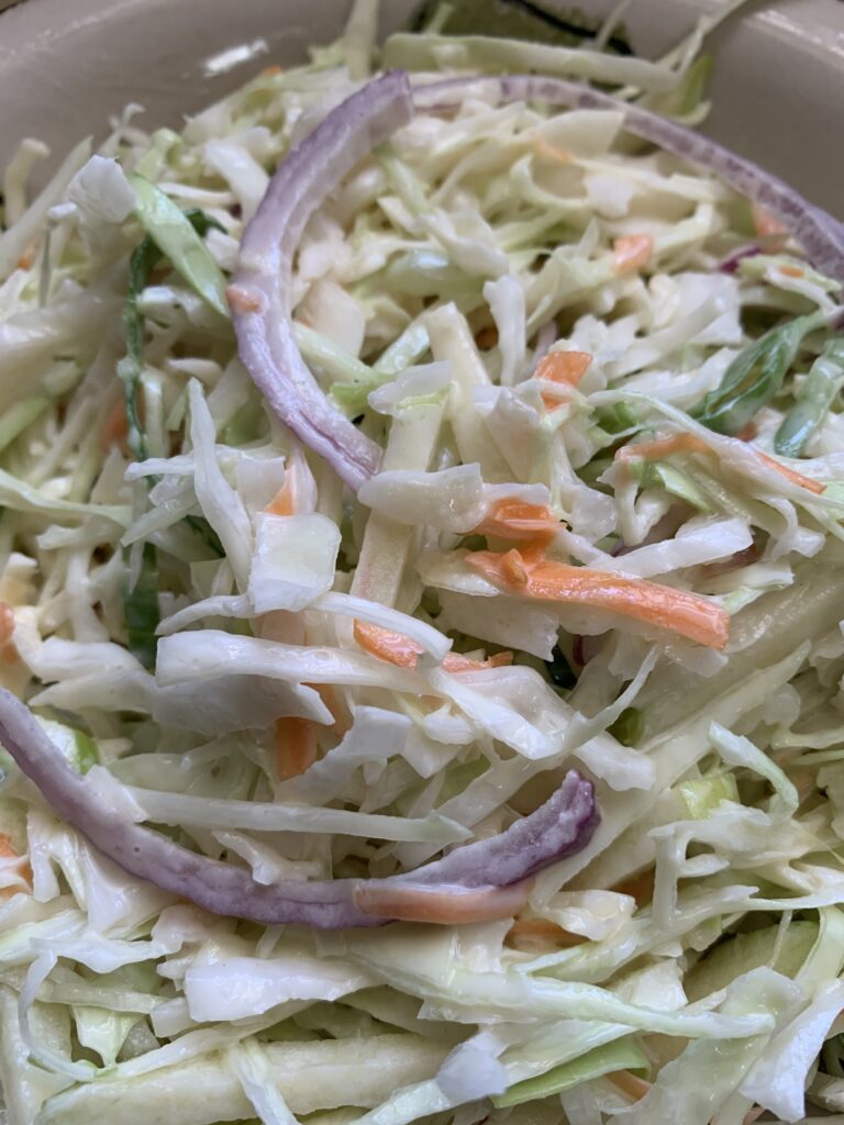 "Shredded cabbage, carrots, purple onion, carrots and green papaya in a round bowl"