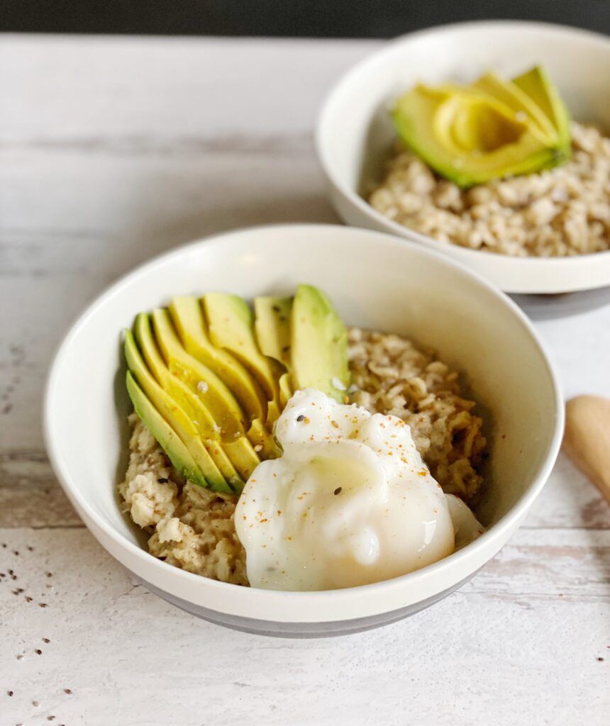 "Savory oatmeal with poached eggs and avocado on a wood grain countertop"