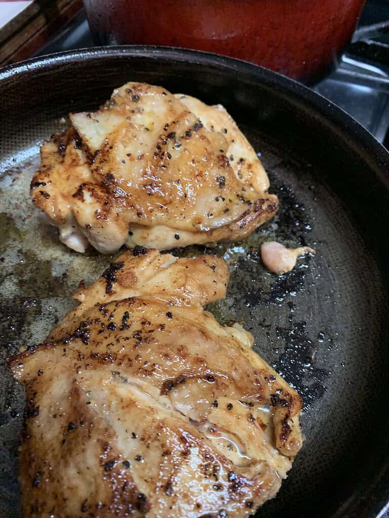 Chicken thighs frying in a pan