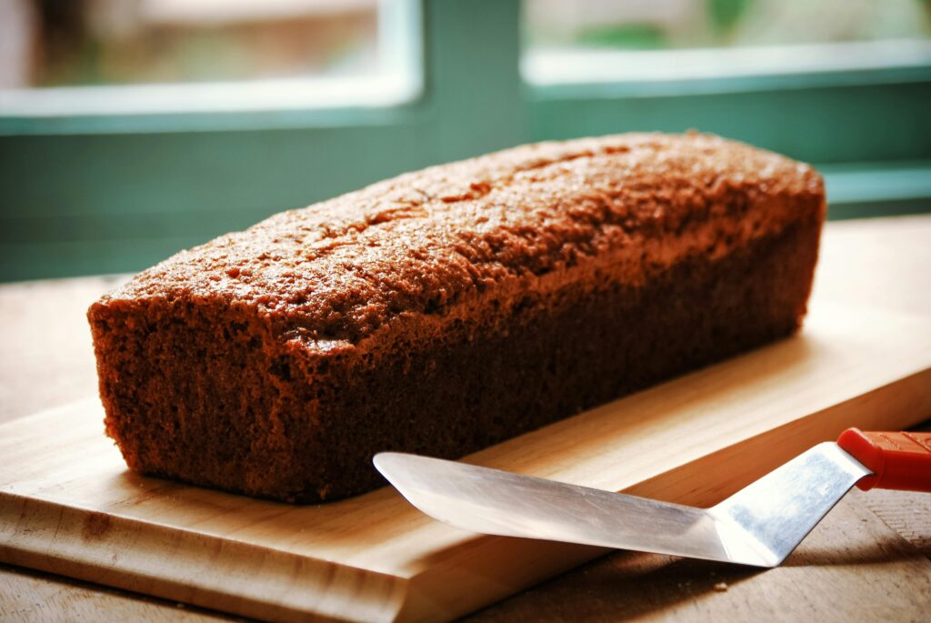 "Banana bread on a cutting board with a spatula on a table"