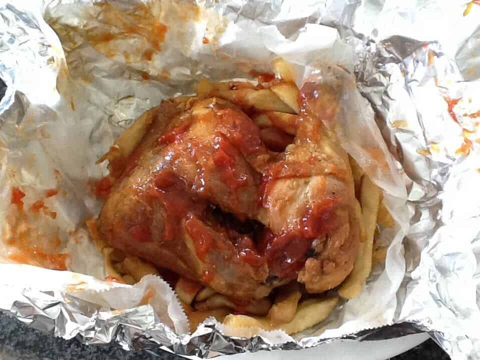 Chicken thigh and leg piece cooked and wrapped in foil covered with ketchup