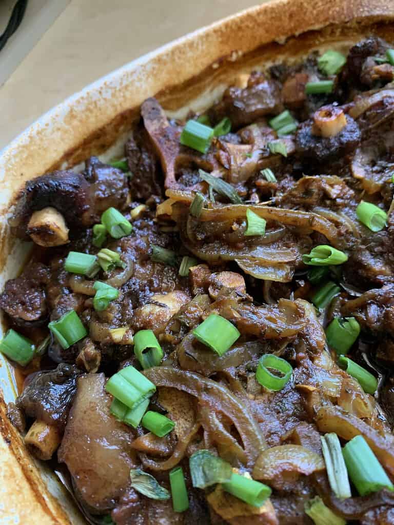 oven baked meat in dish with green onions