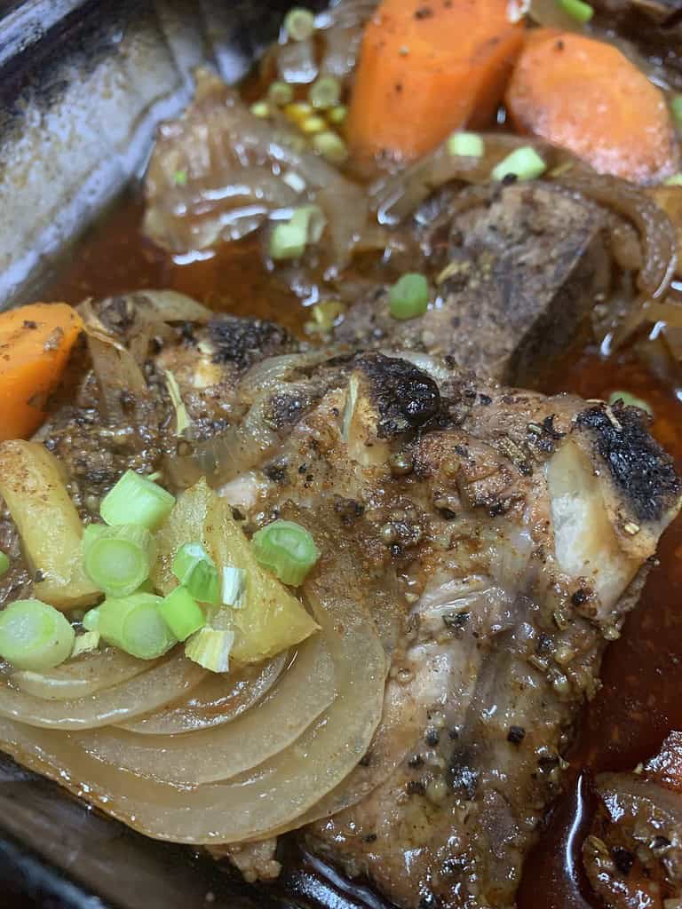 Caribbean spiced braised lamb oven roasted with onions, carrots, apples