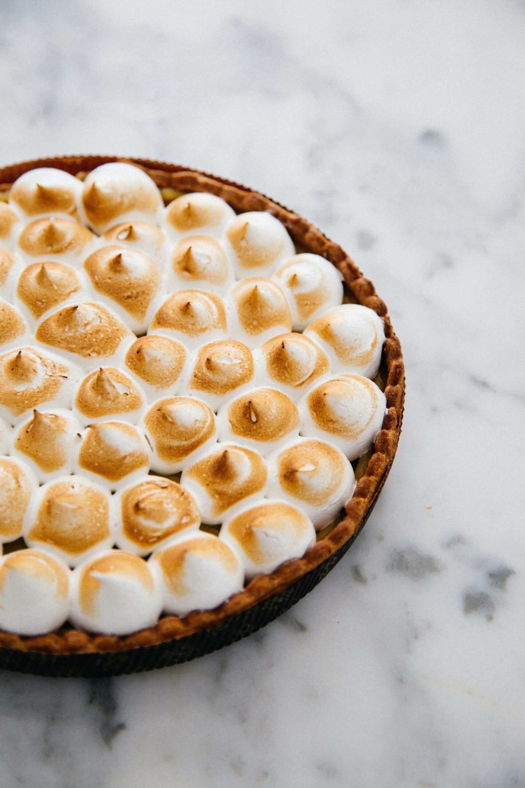 "What are some Easter desserts, a pie sitting on a marble counter top with a golden brown meringue topping"