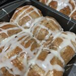 "Bread buns covered in icing sugar in silver baking pans"