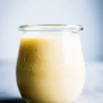 "a jar of creamy dressing on a grayish countertop"